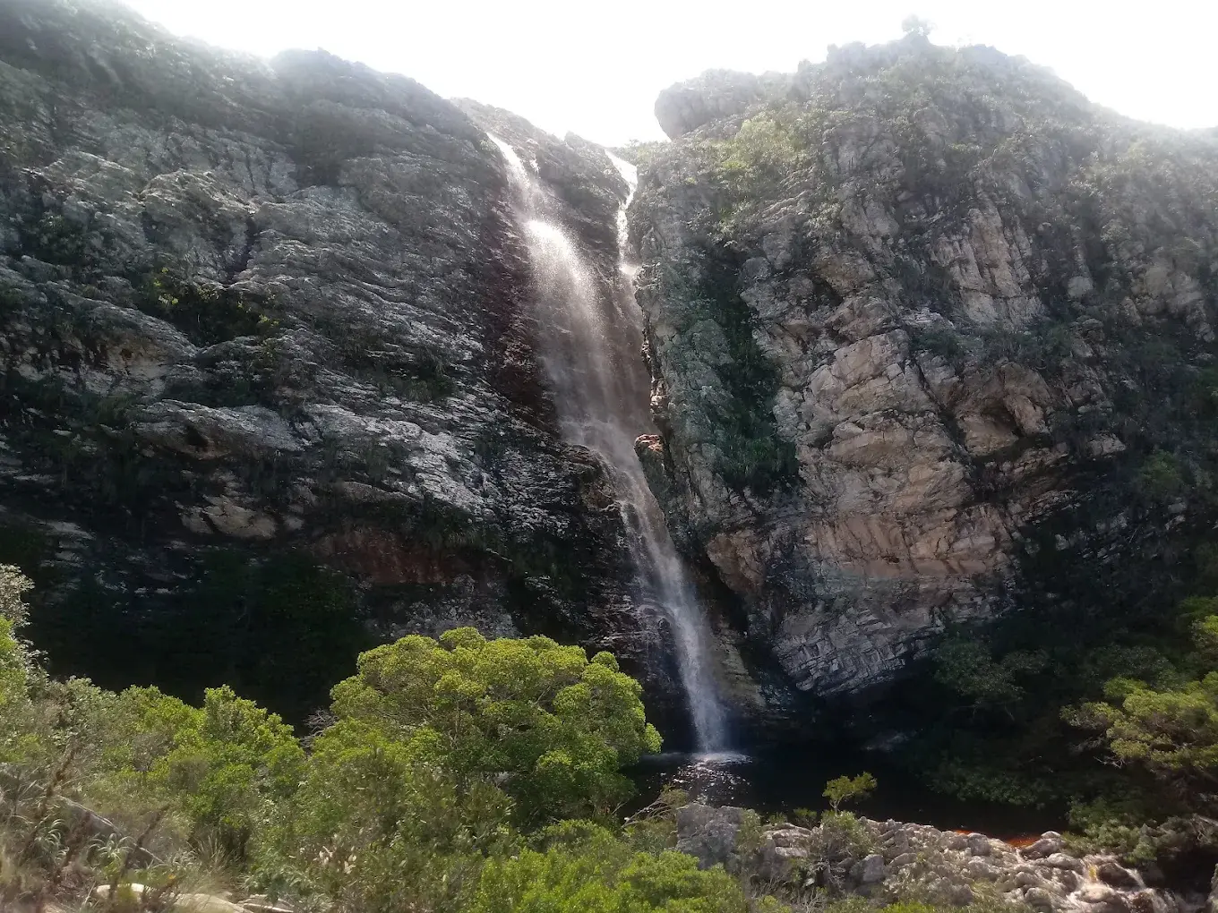 Queda d'água da Cachoeira do Boqueirão caindo entre paredões de pedra até o poço, em Lapinha da Serra