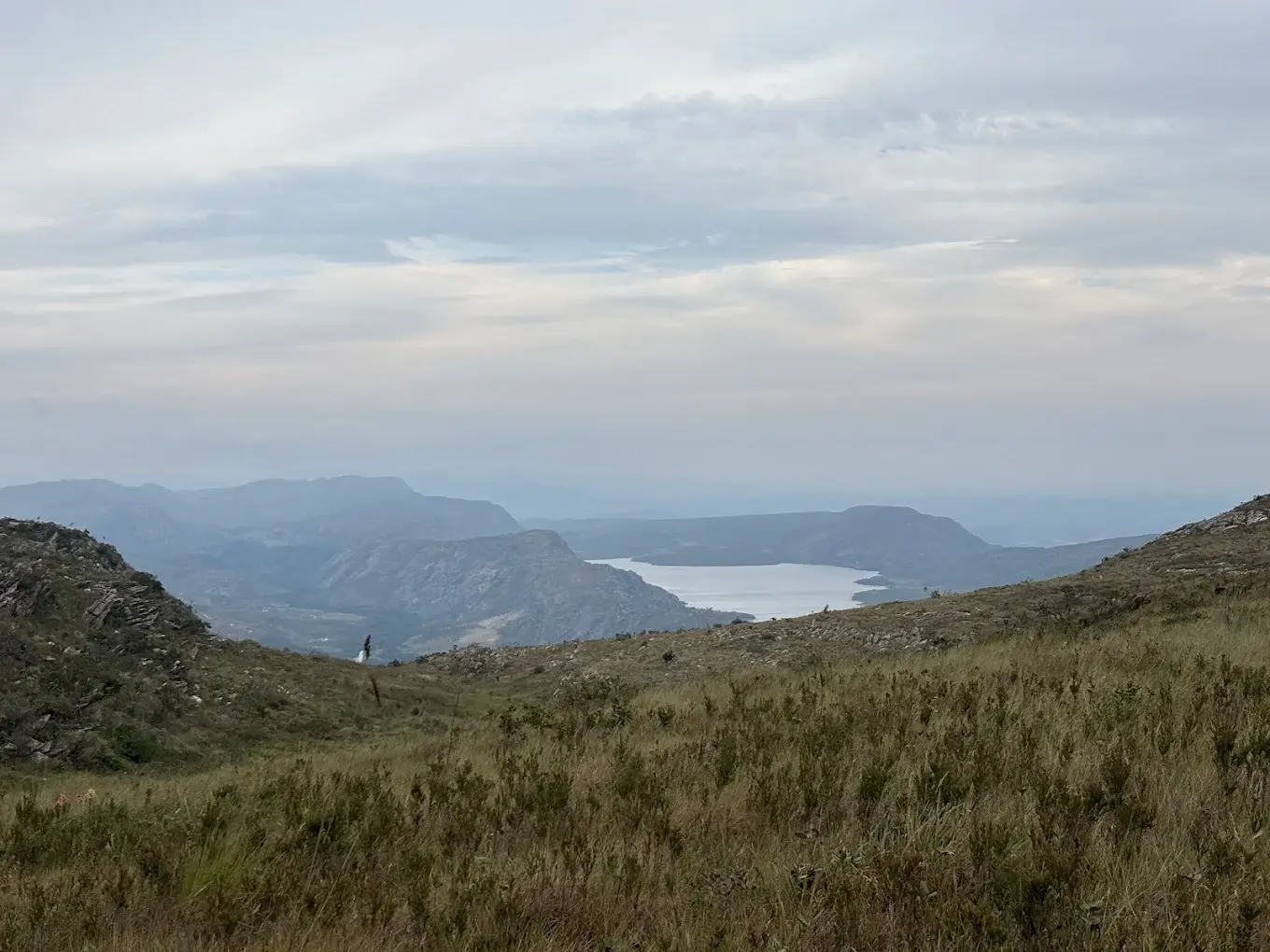 Trecho da trilha do Pico da Lapinha, entre campos rupestres, com a represa ao fundo