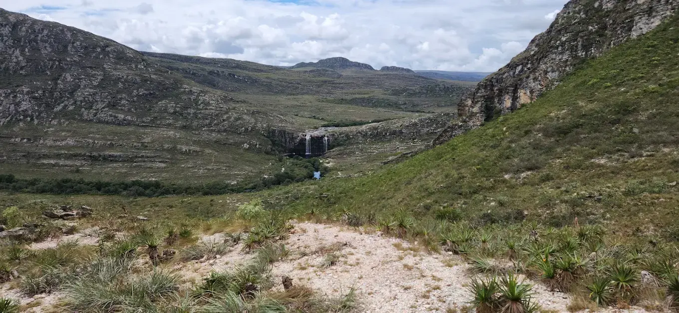 Vista do vale rumo à Cachoeira do Bicame, com a queda visível ao longe entre os campos rupestres