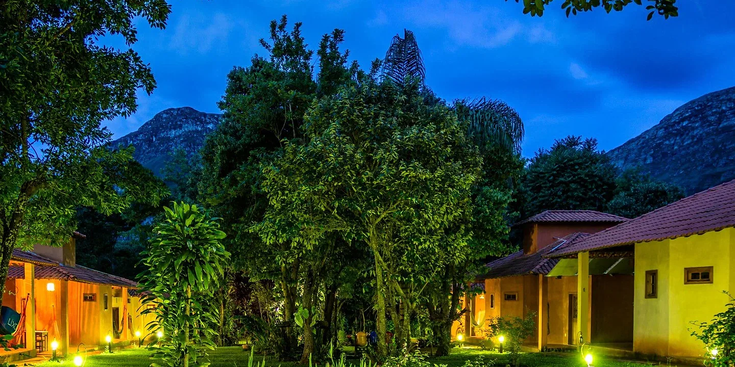 Pousada OPICODOCIPO ao anoitecer, jardim iluminado com a Serra do Espinhaço ao fundo, em Lapinha da Serra