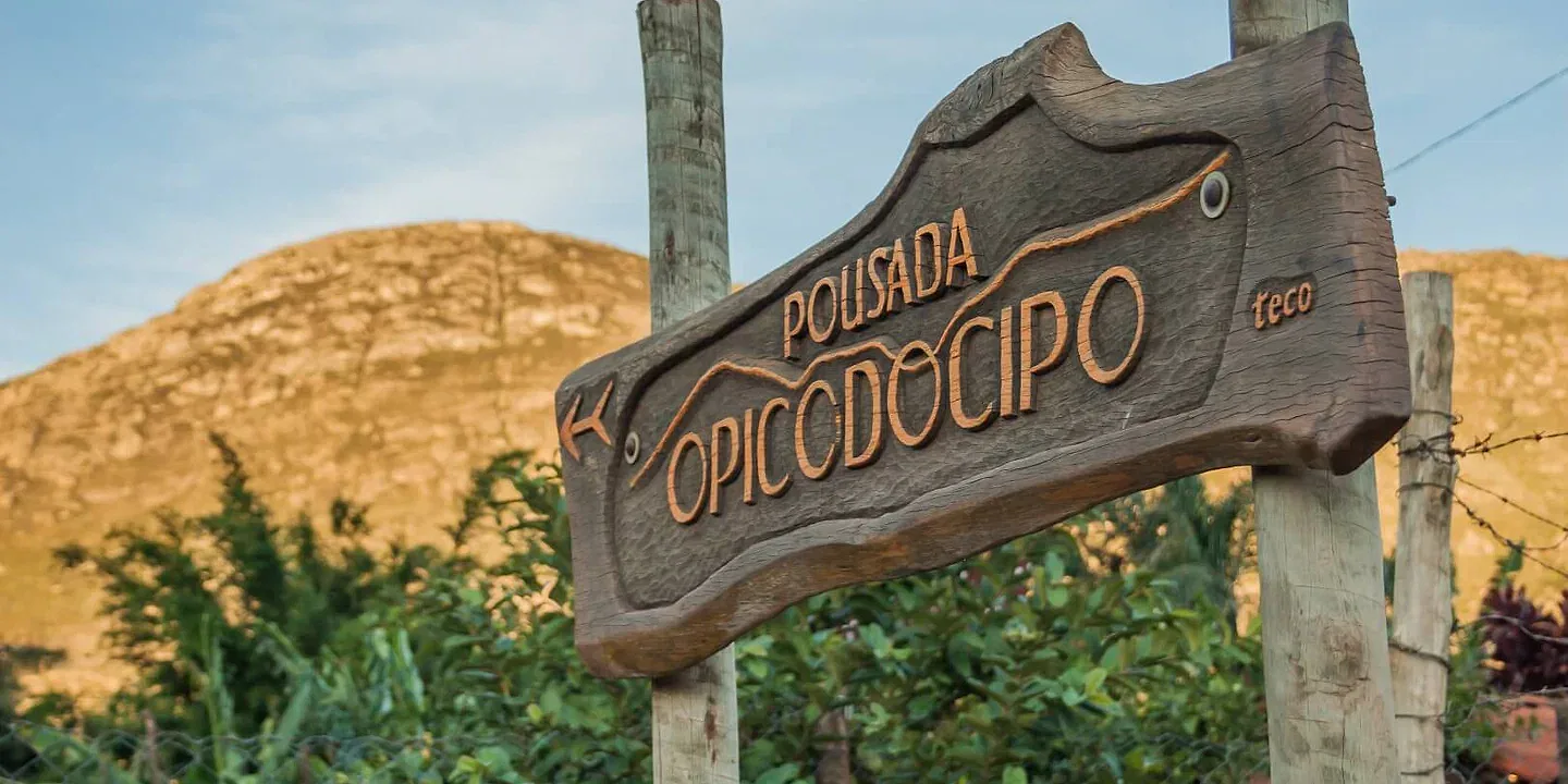 Placa de entrada da Pousada OPICODOCIPO em Lapinha da Serra, com a Serra do Espinhaço ao fundo